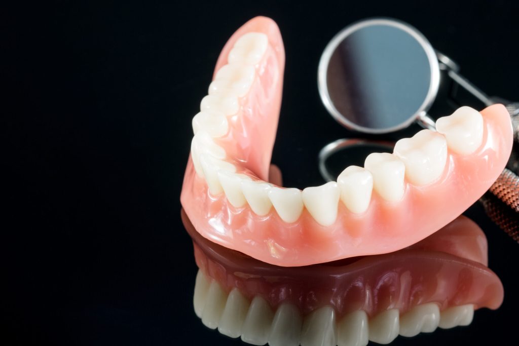 Prótese dentária inferior com dentes brancos sobre fundo escuro