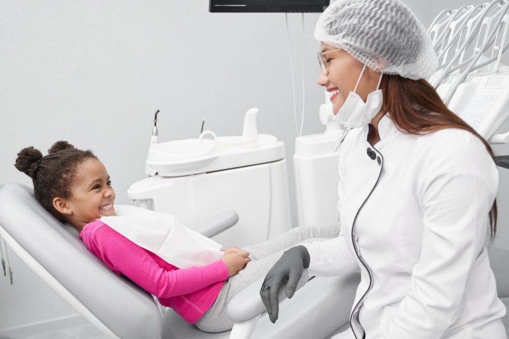 Menina sorridente sendo atendida por dentista em ambiente acolhedor na Sorridents Porto Alegre, representando a odontopediatria humanizada.