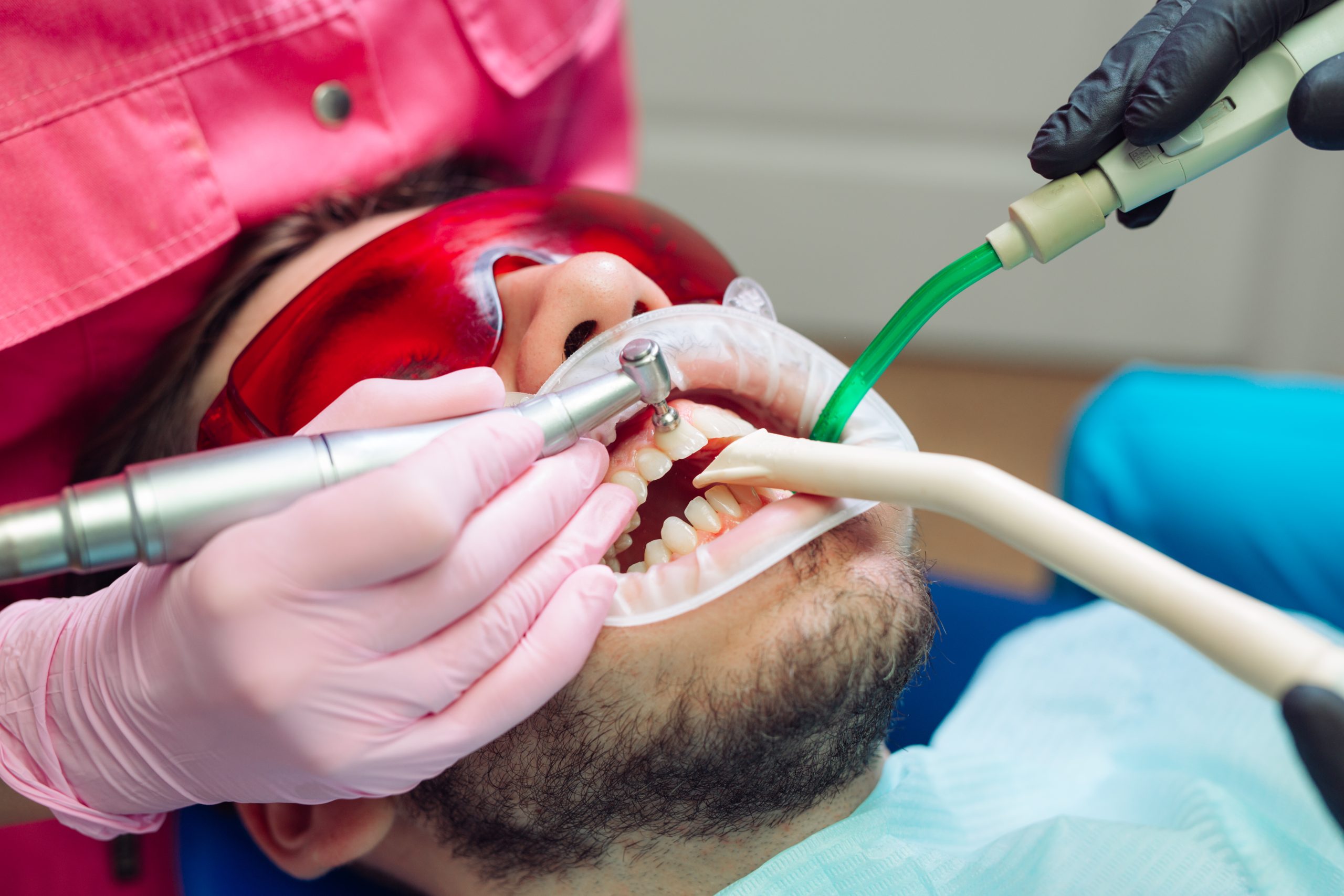 Paciente realizando limpeza dentária profissional em consultório odontológico de Porto Alegre, usando proteção ocular e instrumentos de alta precisão.
