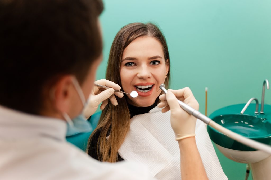 Mulher sendo atendida por dentista durante procedimento de limpeza dentária em consultório moderno
